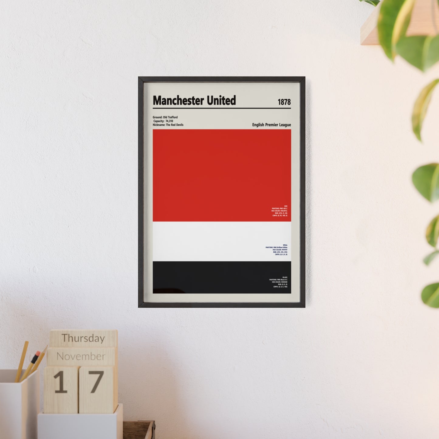 Framed Manchester United colour swatch print hanging on a wall above a desk shelf