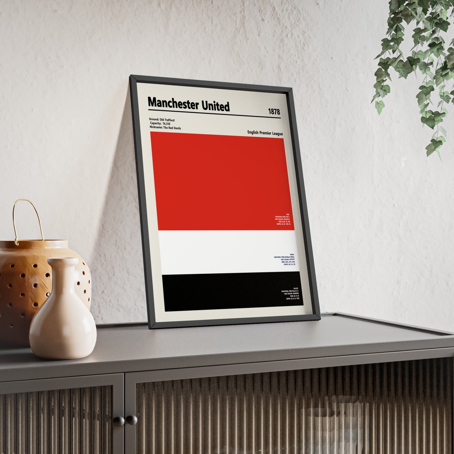 Framed Manchester United colour swatch print leaning against a sideboard in a modern living room