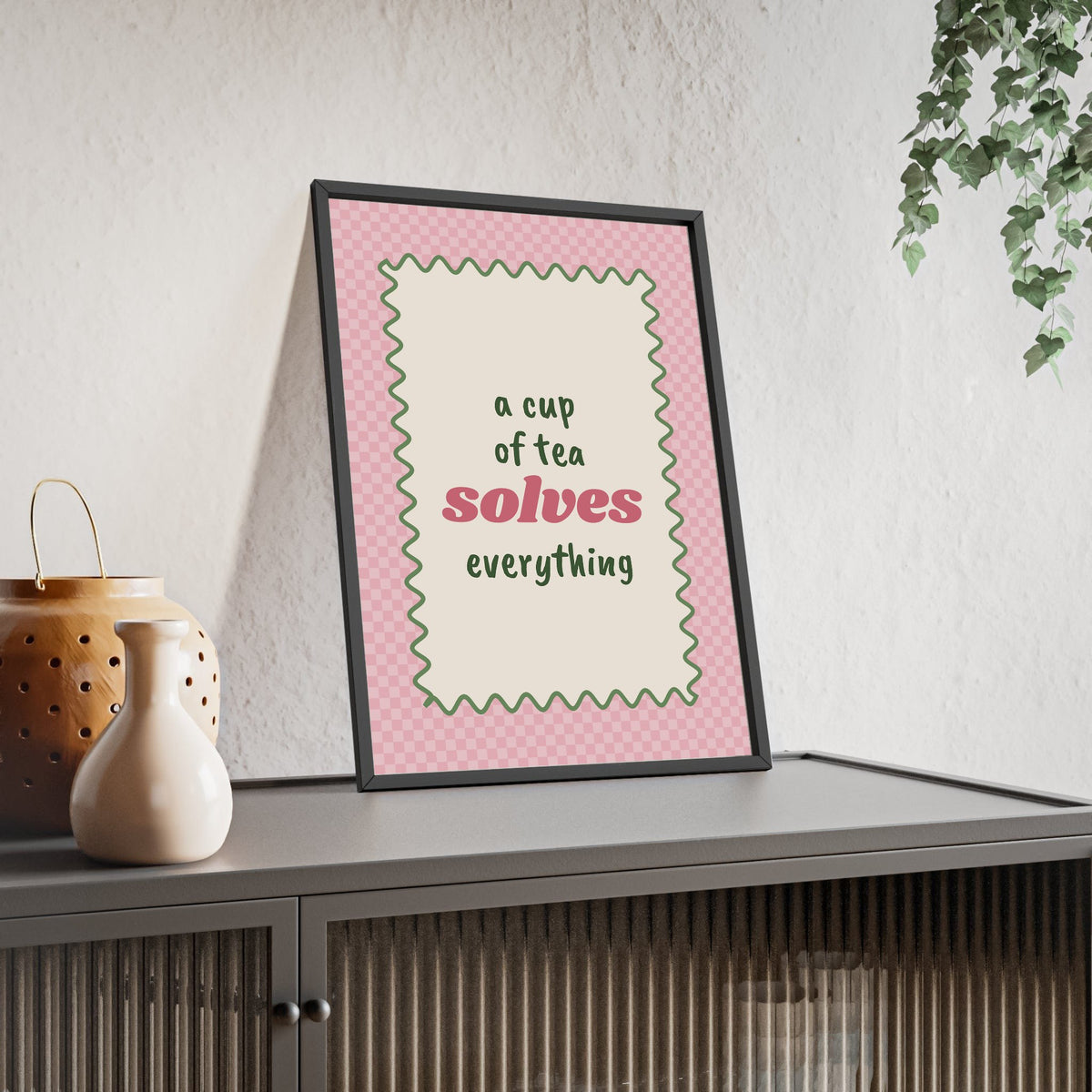 A Cup of Tea Solves Everything Print framed and leaning on a sideboard