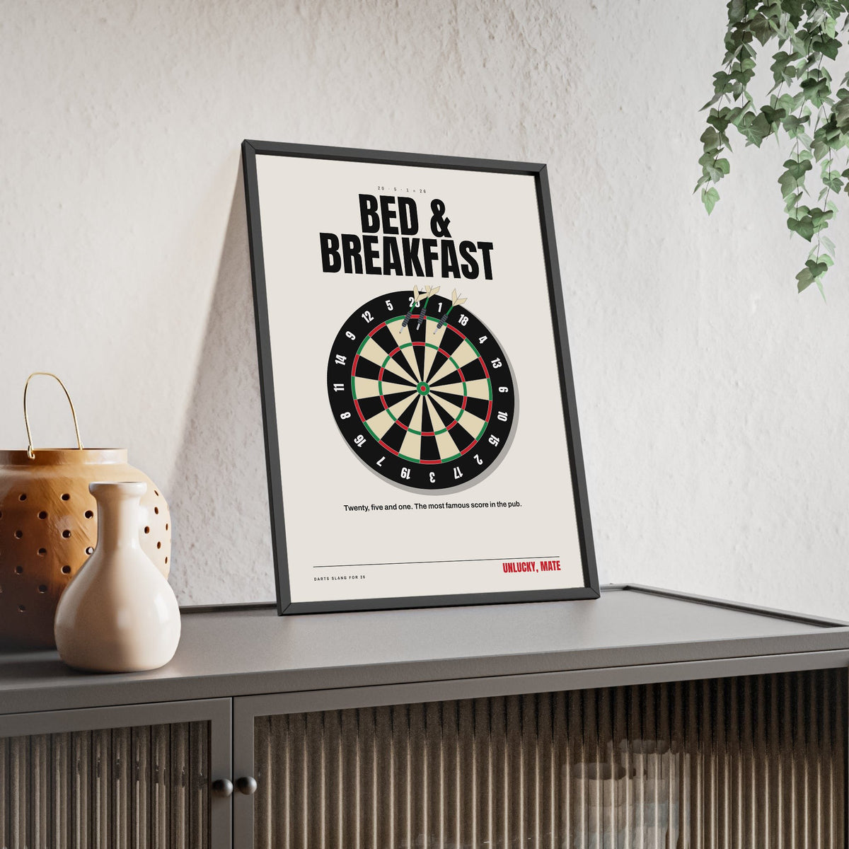 Bed and Breakfast 26 Darts print framed and leaning on a sideboard