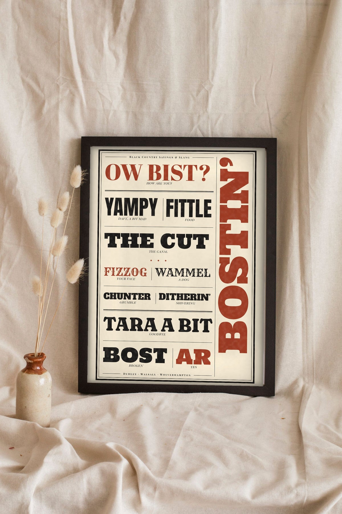 Black Country Sayings Print in a black frame propped up on linen