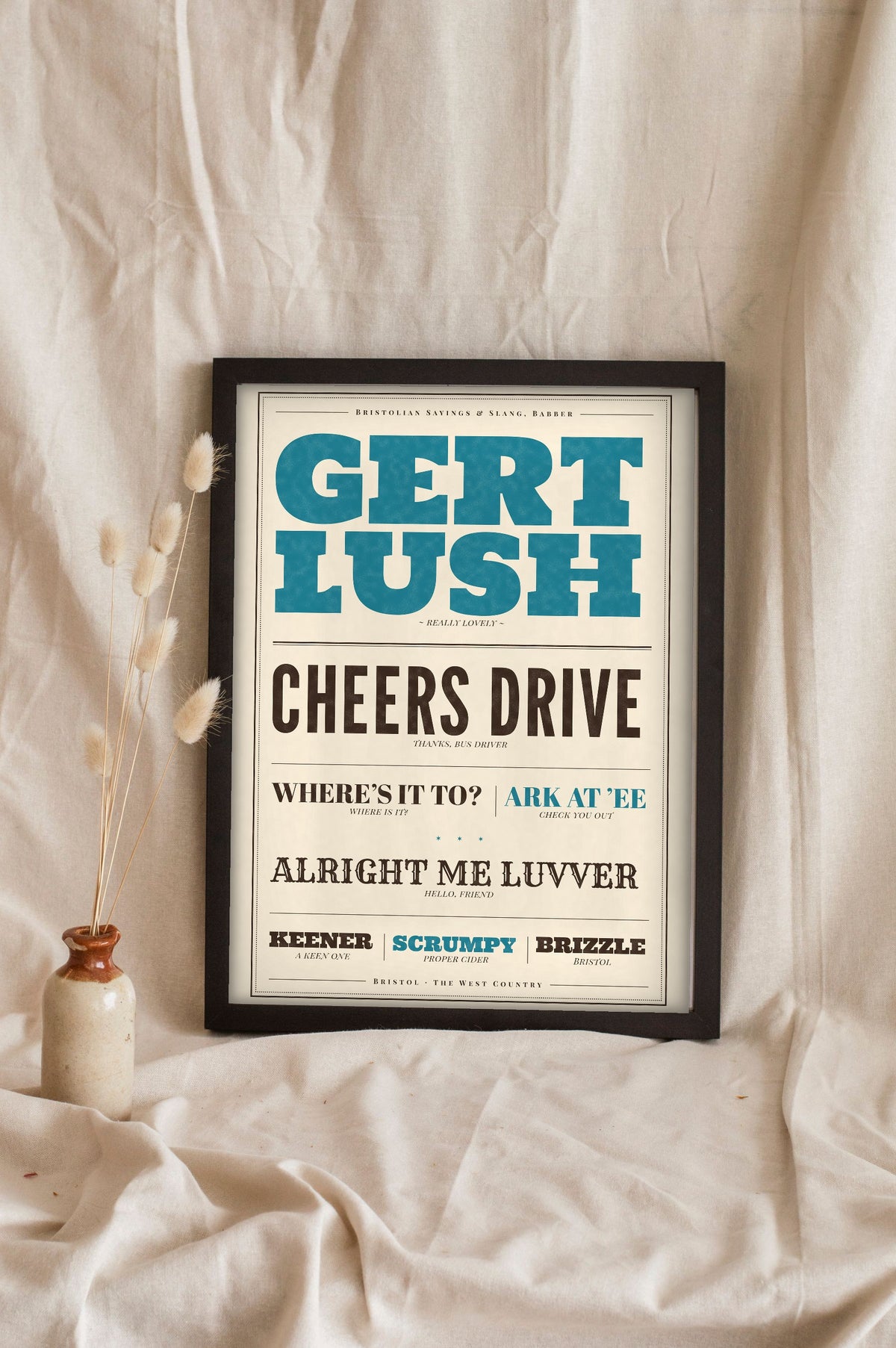 Bristol Sayings Print in a black frame propped up on linen