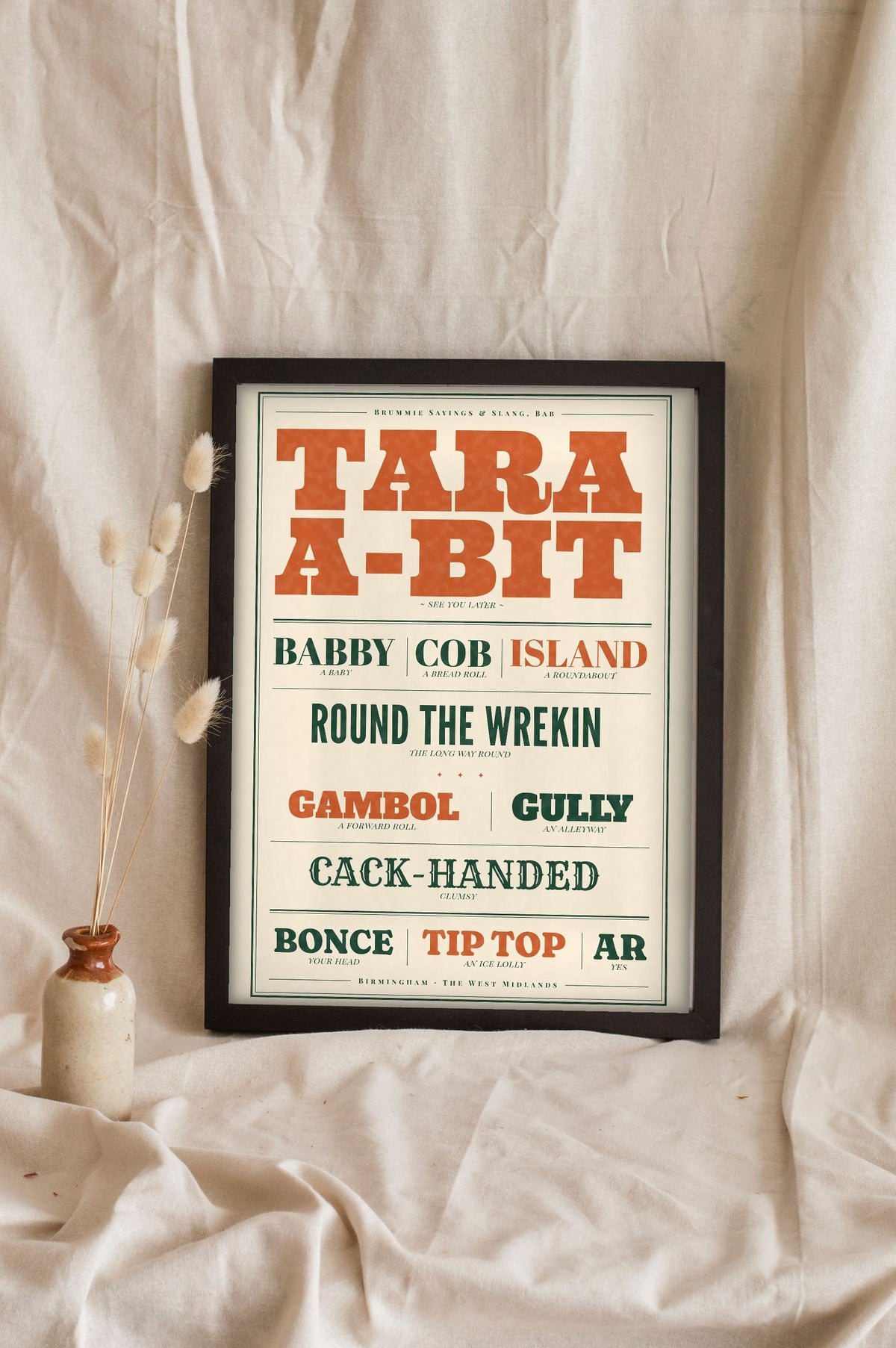 Brummie Sayings Print in a black frame propped up on linen