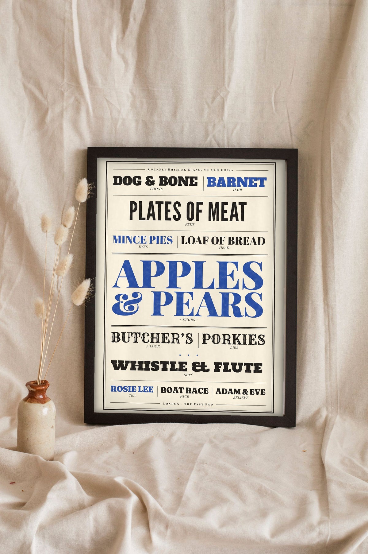 Cockney Rhyming Slang Poster in a black frame propped up on linen