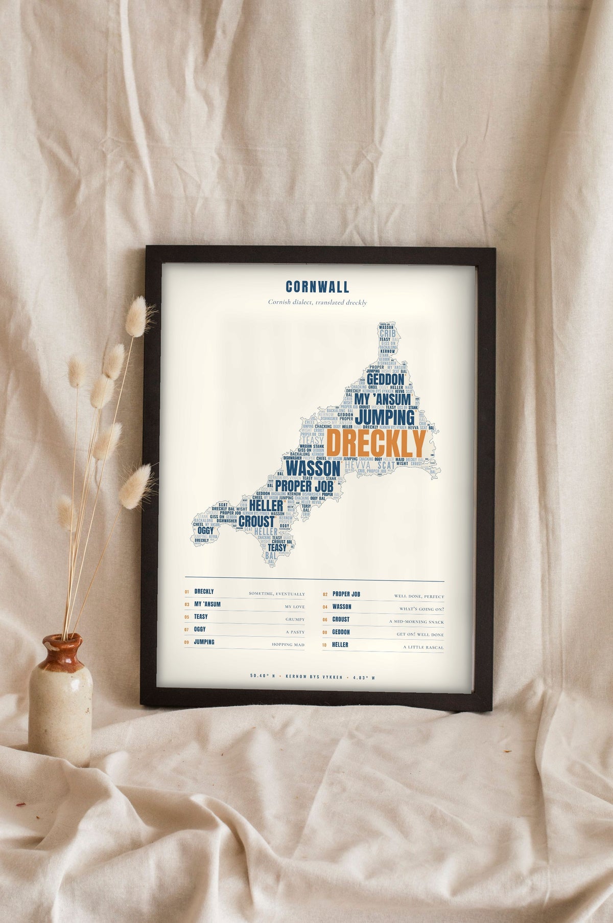 Cornish Sayings Print in a black frame propped up on linen