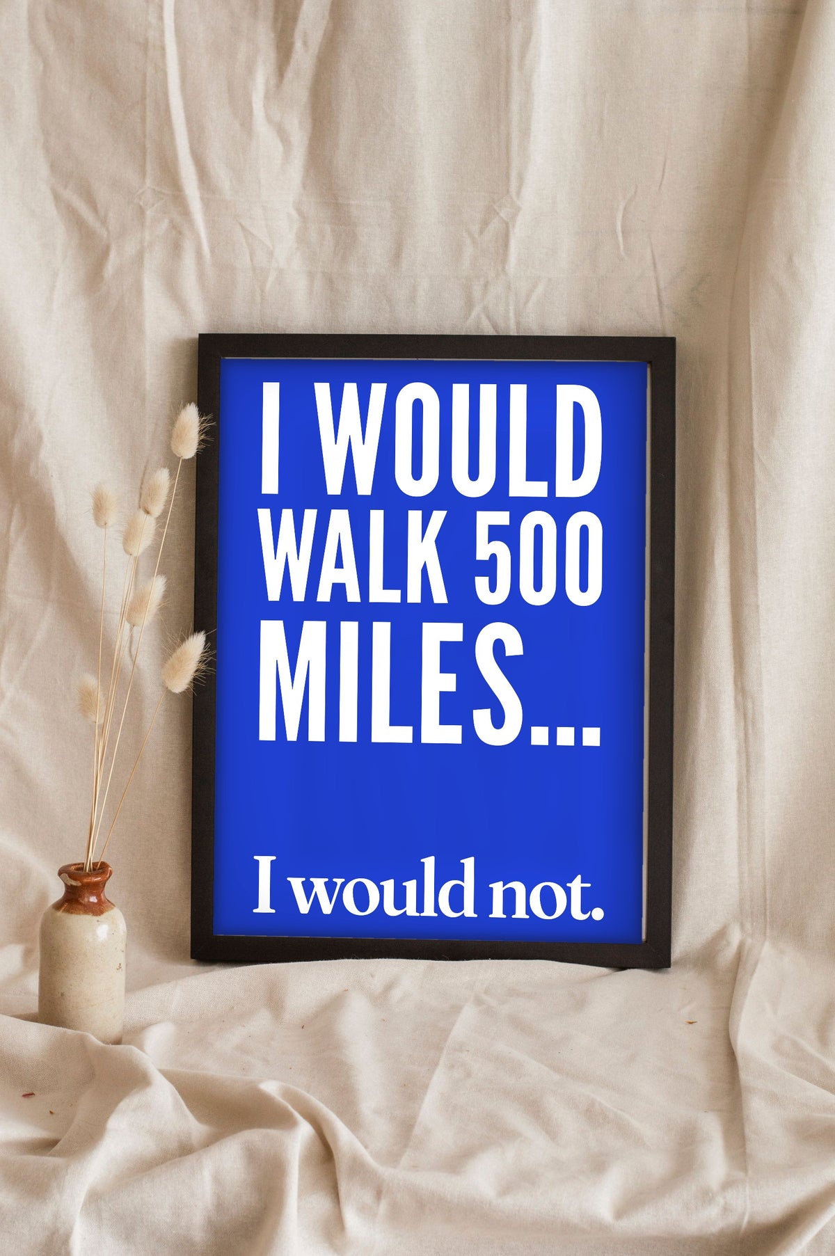 Funny 500 Miles lyric print in a black frame propped up on linen