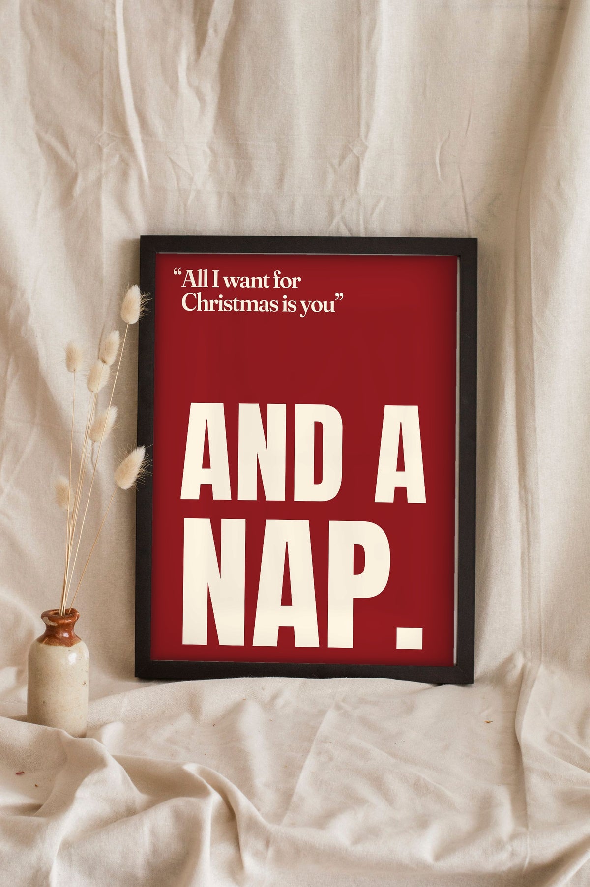 Funny All I Want for Christmas Is You lyric print in a black frame propped up on linen