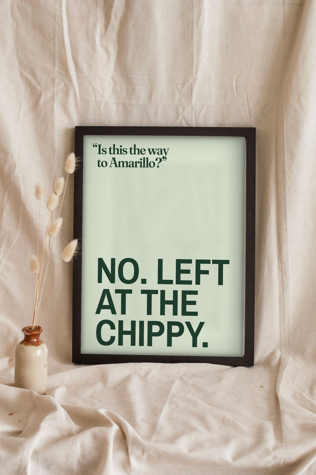 Funny Amarillo lyric print in a black frame propped up on linen
