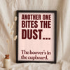 Funny Another One Bites the Dust lyric print in a black frame propped up on linen