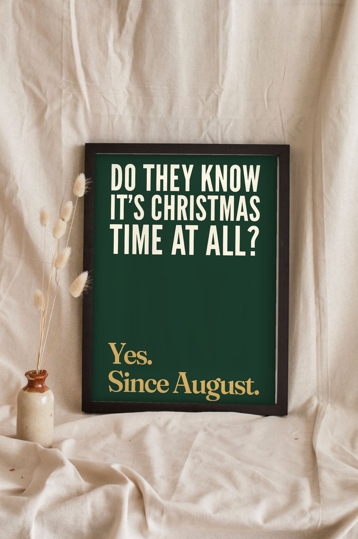 Funny Do They Know It's Christmas? lyric print in a black frame propped up on linen