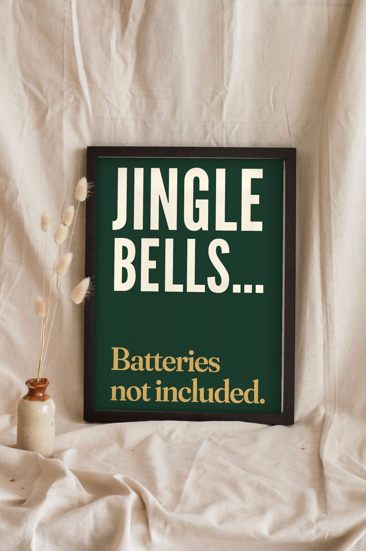 Funny Jingle Bells lyric print in a black frame propped up on linen