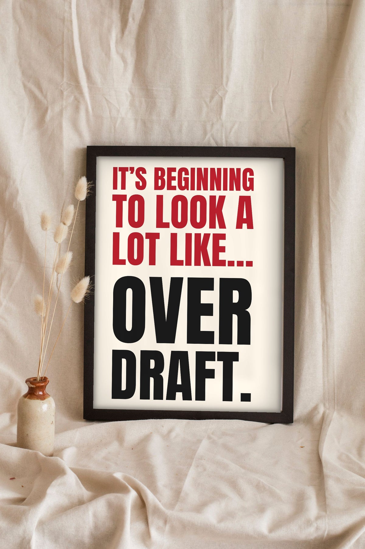 Funny It's Beginning to Look a Lot Like Christmas lyric print in a black frame propped up on linen