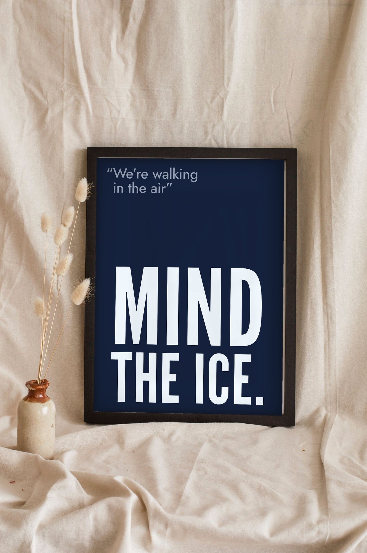 Funny Walking in the Air lyric print in a black frame propped up on linen