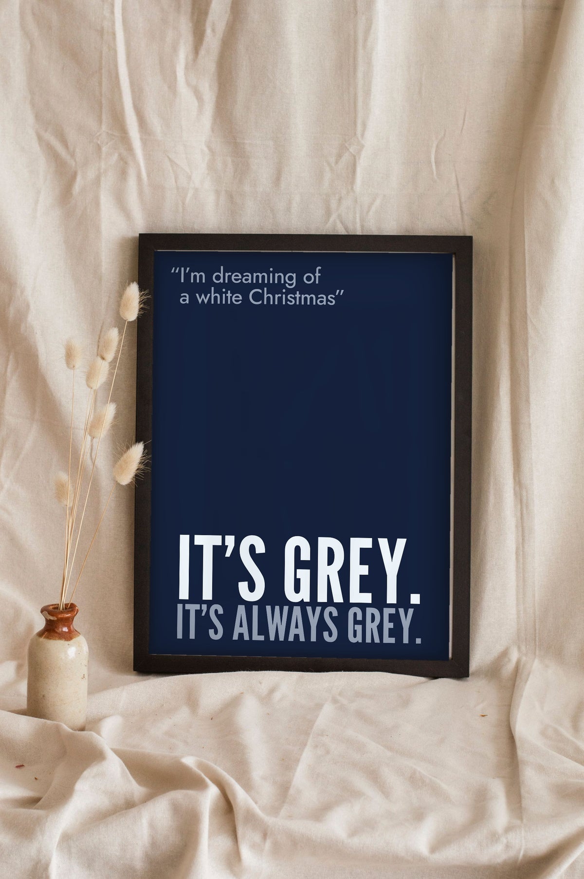 Funny White Christmas lyric print in a black frame propped up on linen