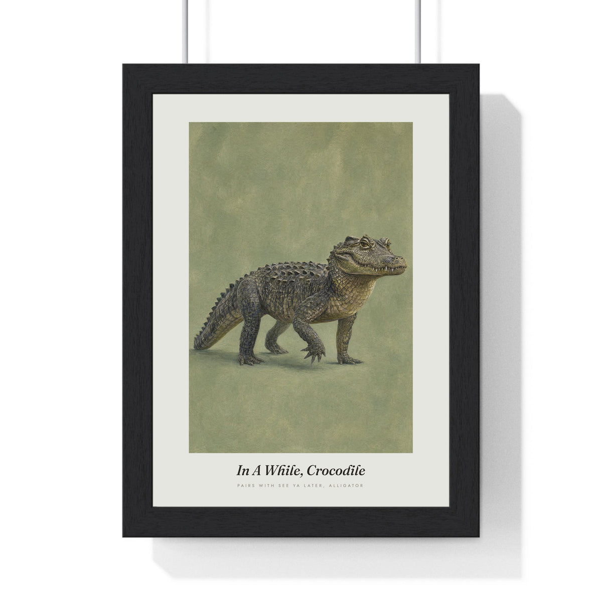 In a While Crocodile Print framed in a black frame, ready to hang