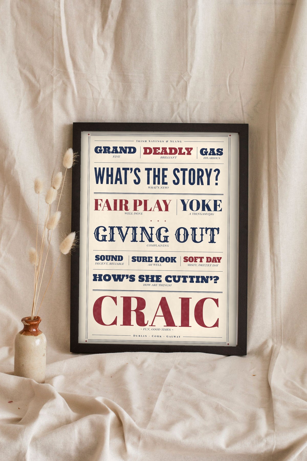 Irish Slang Print in a black frame propped up on linen