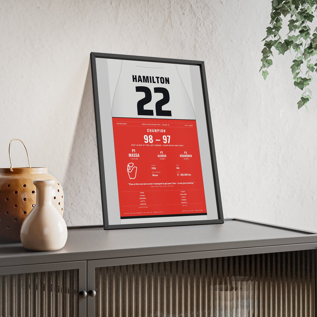 Lewis Hamilton 2008 Brazilian Grand Prix World Champion Poster - 22 Race Suit Print framed and leaning on a sideboard