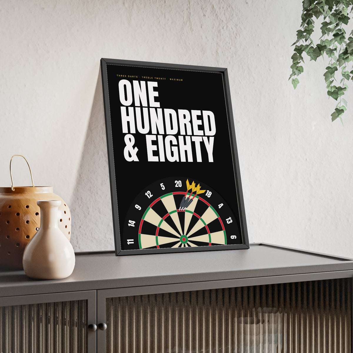 One Hundred and Eighty Darts print framed and leaning on a sideboard