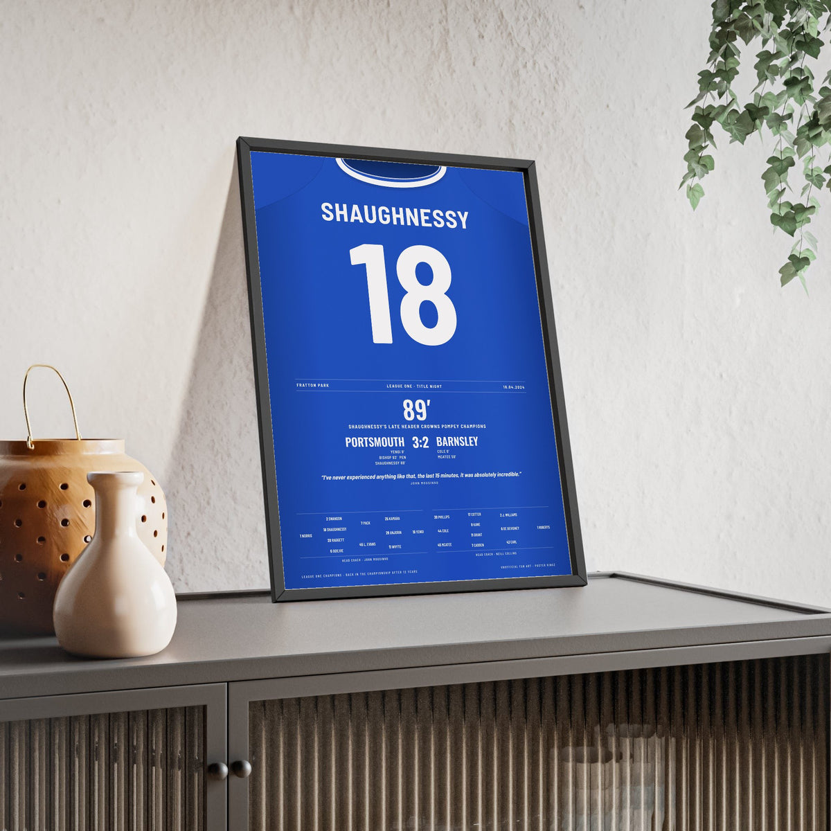 Portsmouth League One Champions 2024 Poster - Conor Shaughnessy 18 Shirt Print framed and leaning on a sideboard