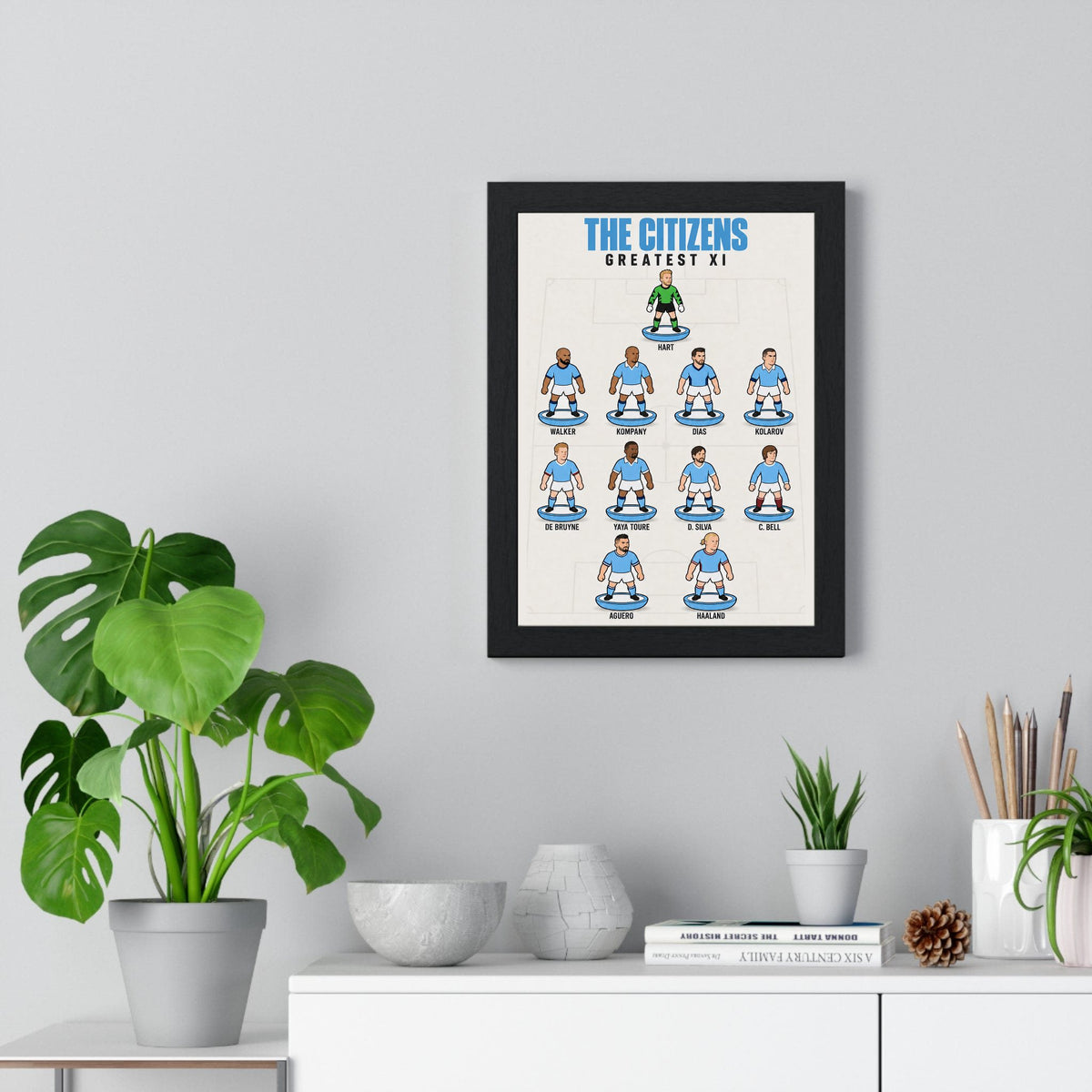Manchester City Greatest XI poster framed on a living room wall