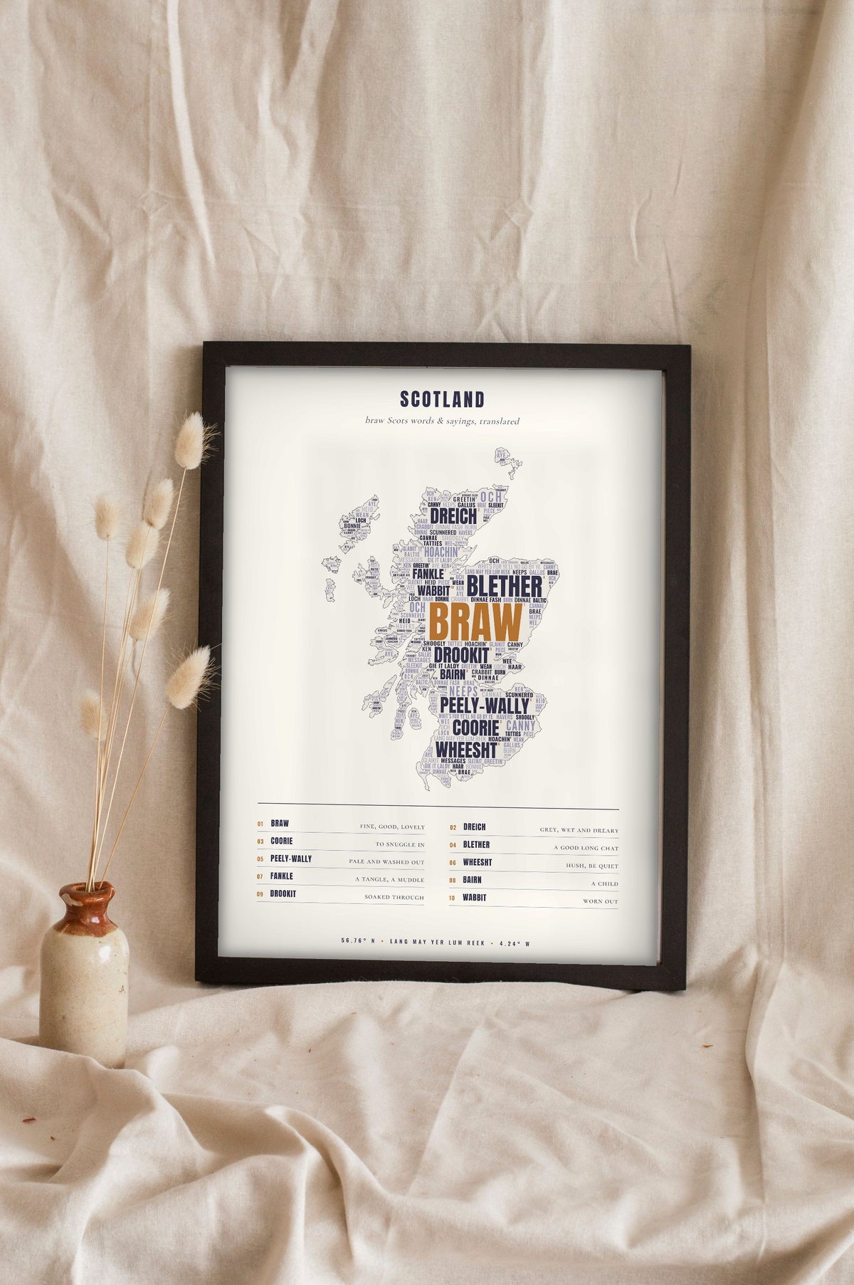 Scottish Sayings Print in a black frame propped up on linen