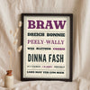 Scottish Slang Print in a black frame propped up on linen