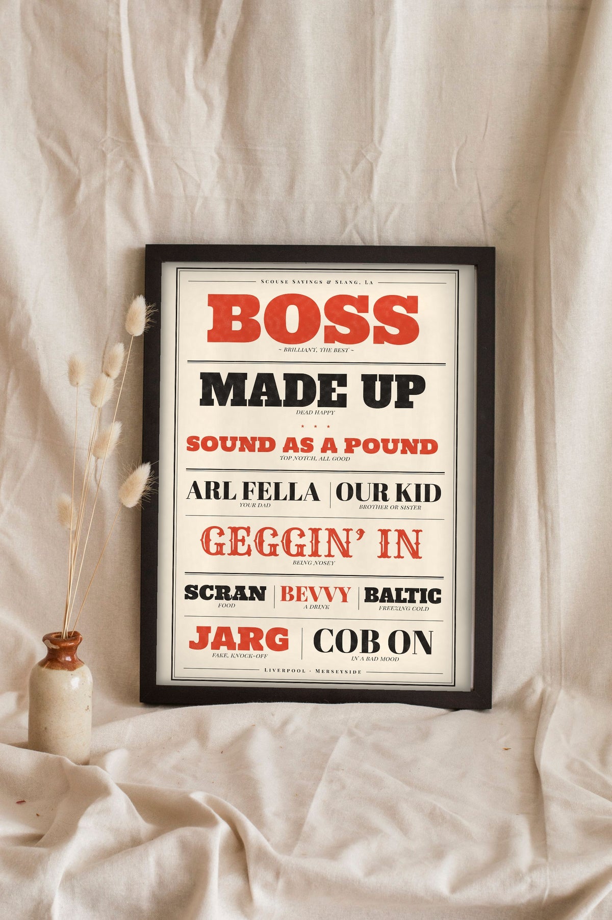 Scouse Sayings Print in a black frame propped up on linen