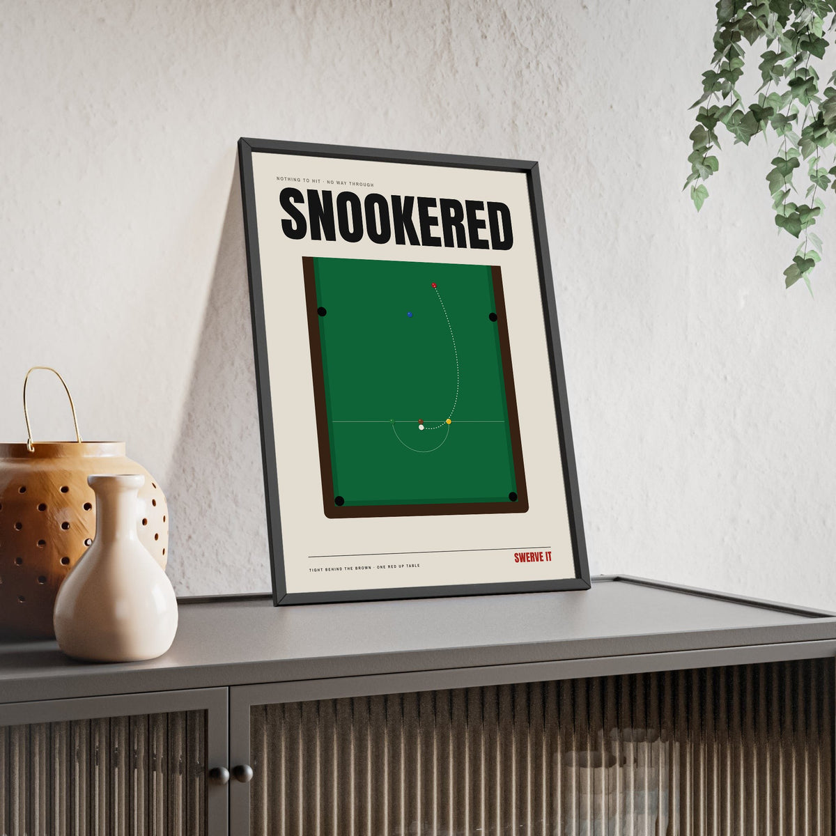 Snookered print framed and leaning on a sideboard