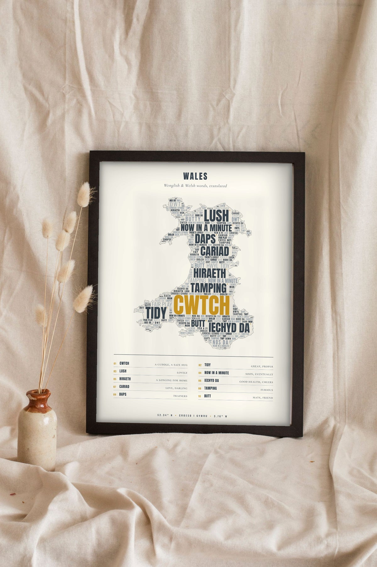 Welsh Sayings Print in a black frame propped up on linen